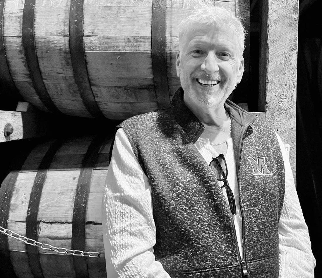 Jim standing beside whiskey barrels